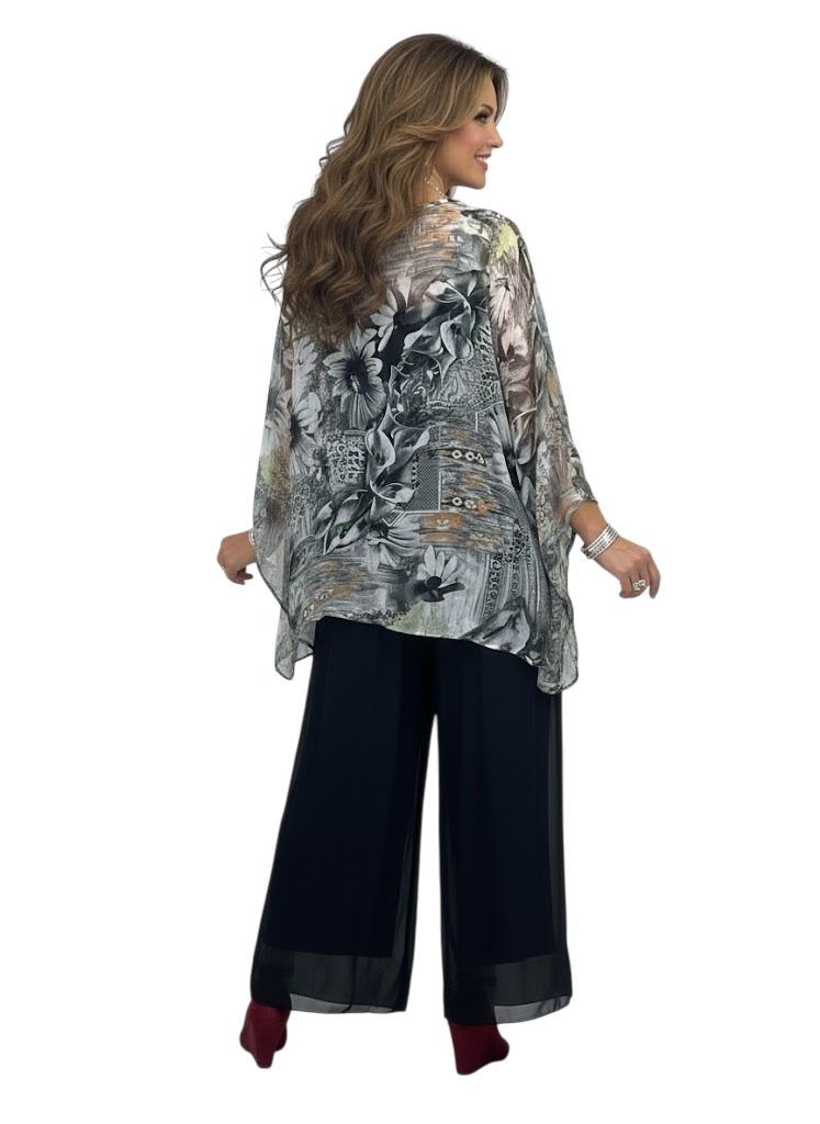 Woman wearing a floral patterned top and black pants on a white background