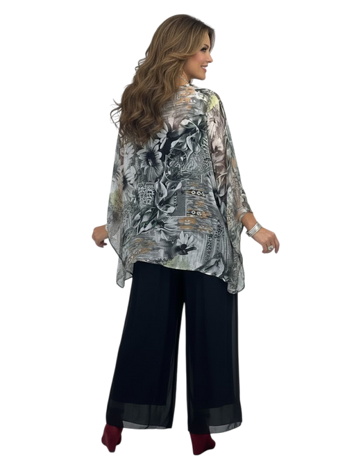 Woman wearing a floral patterned top and black pants on a white background