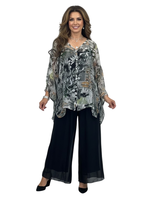 Woman wearing a patterned top and black pants on a white background